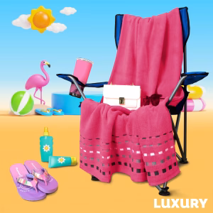 Toalla de algodón egipcio color rosa mexicano de la línea Luxury Zantelo para playa o baño sobre una silla azul.